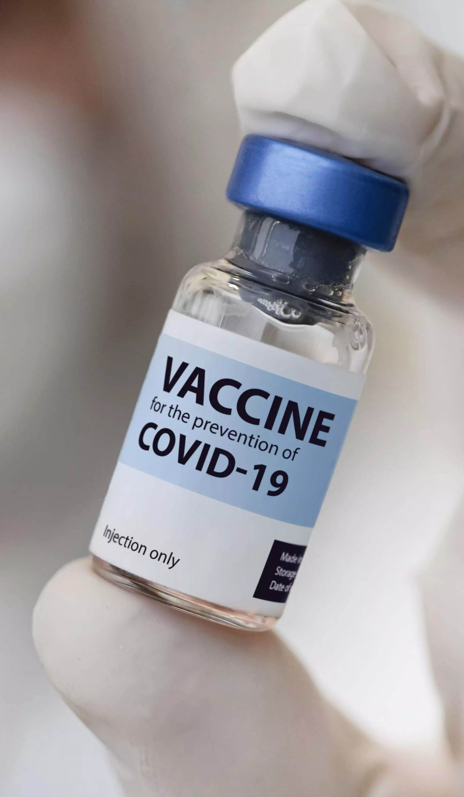 Person in gloves holding a COVID-19 vaccine